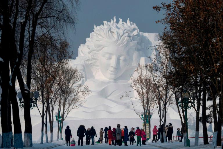 Turistas caminan frente a una escultura de hielo el 4 de enero de 2020 antes de la apertura del Festival Anual de Hielo y de Nieve de Harbin en China.