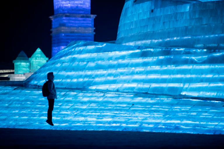 Un turista salta frente a una escultura de hielo en el Festival de Harbin, en China el 5 de enero de 2020.
