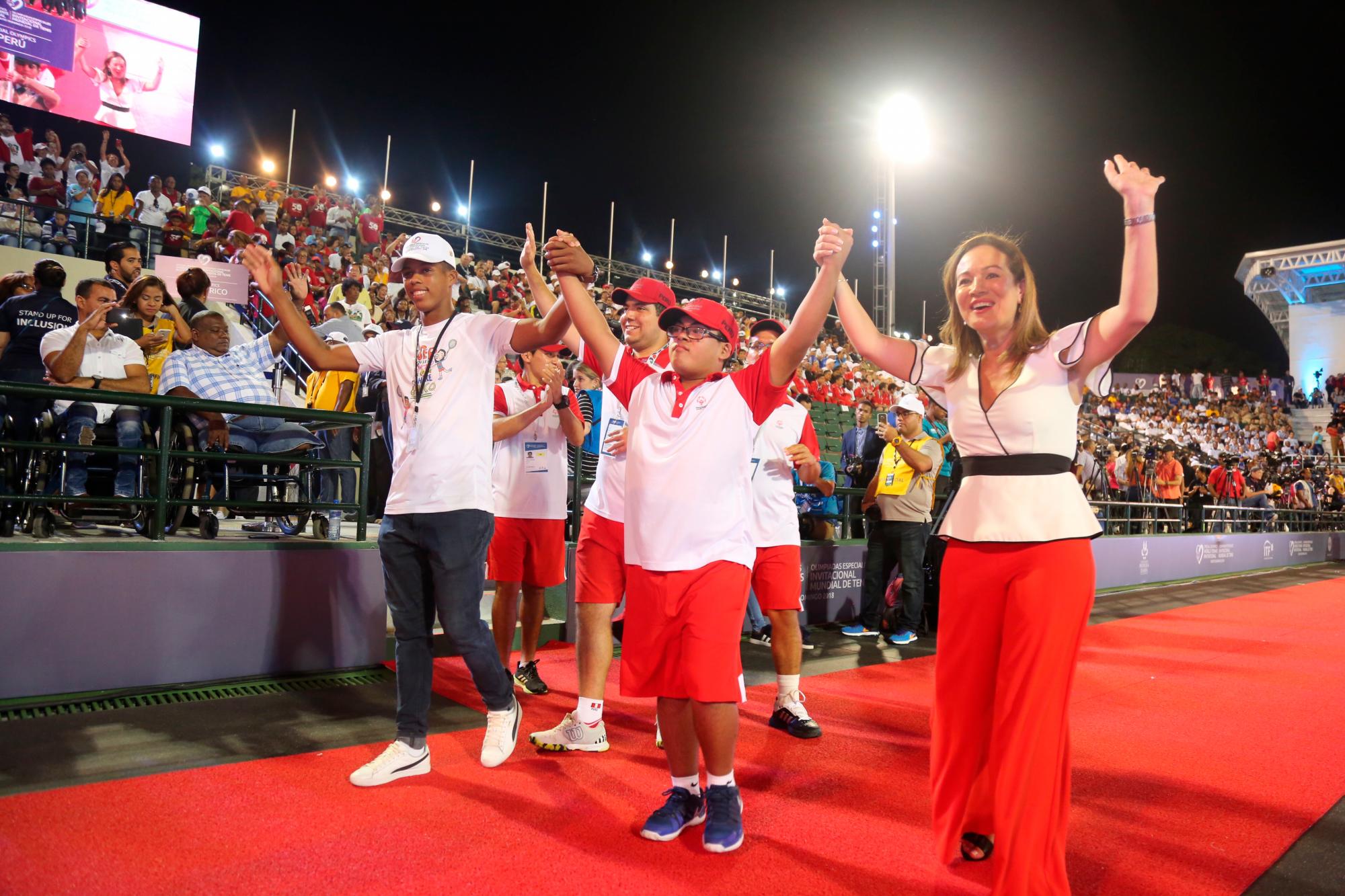 La presidenta de Olimpiadas Especiales América Latina, Claudia Echeverry, a la derecha, desfila con la delegación de Perú en la ceremonia de apertura del Invitacional Mundial de Tenis de Olimpiadas Especiales el domingo 11 de noviembre en el centro de tenis del Parque del Este.