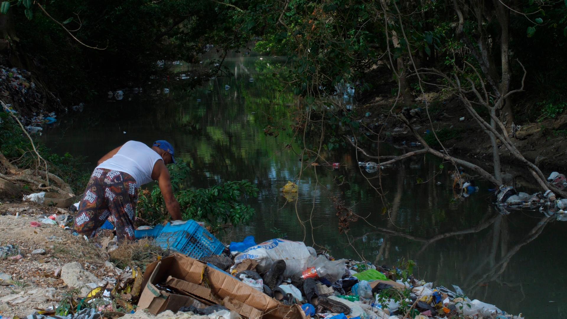 Momentos en que un comunitario arroja basura en la cañada de Guajimía.