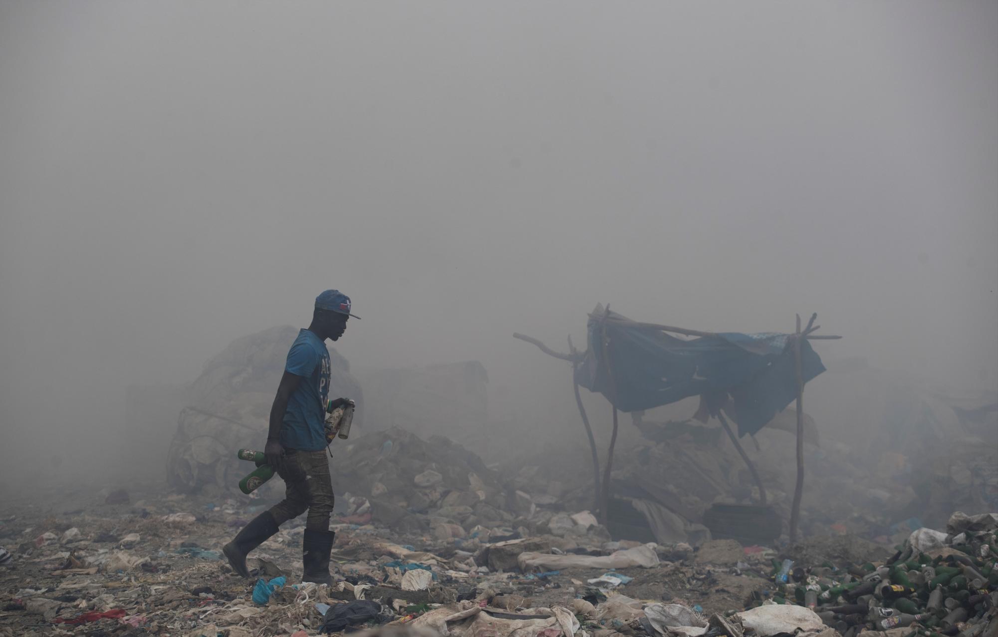 Un trabajador busca entre la basura metales para reciclar mientras se registra un gigantesco incendio en el vertedero Duquesa. 
