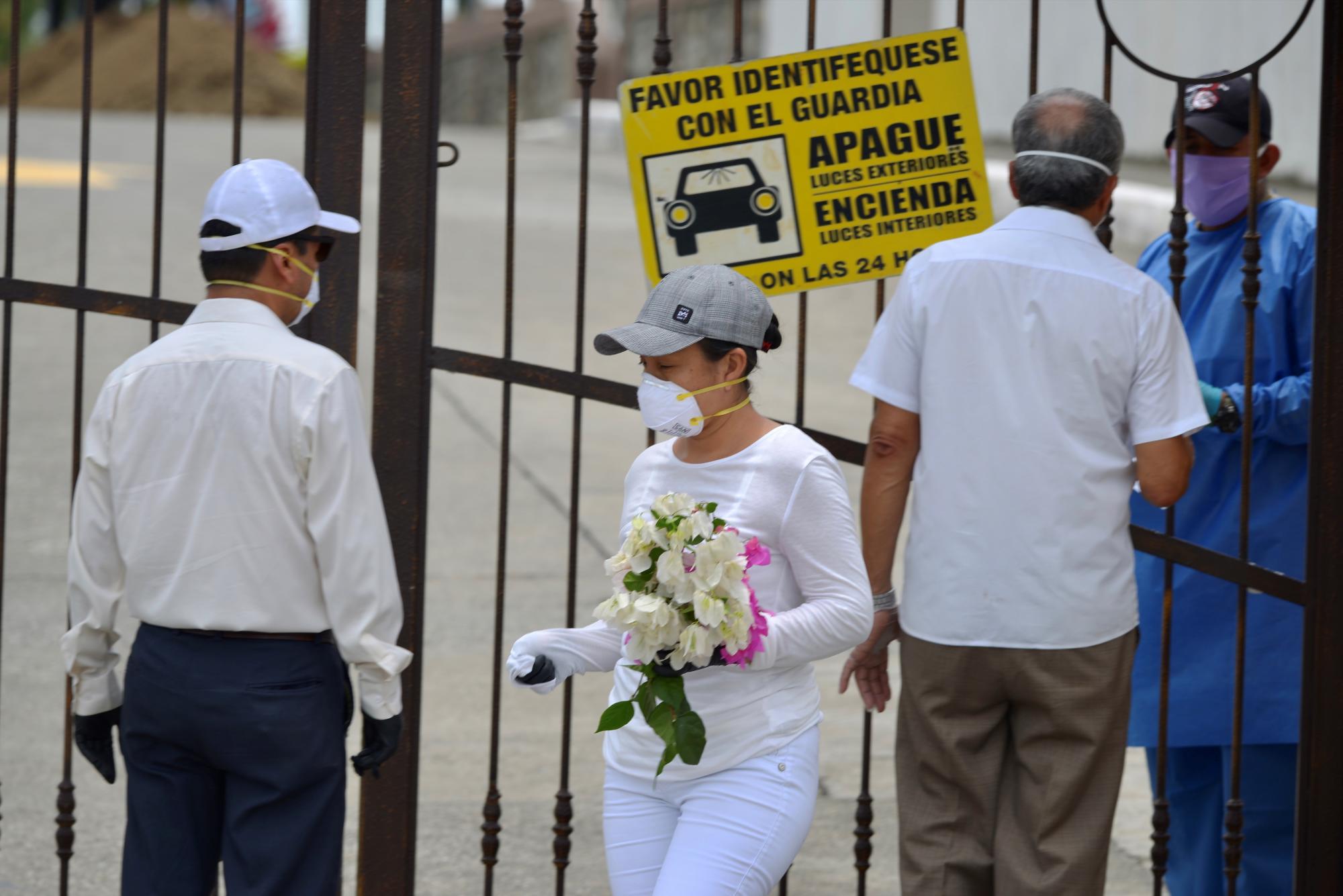  Familiares con tapabocas hacen consultas este miércoles a un guardia de seguridad de un cementerio, para poder despedir a sus seres queridos, en Guayaquil (Ecuador). (EFE/Marcos Pin)