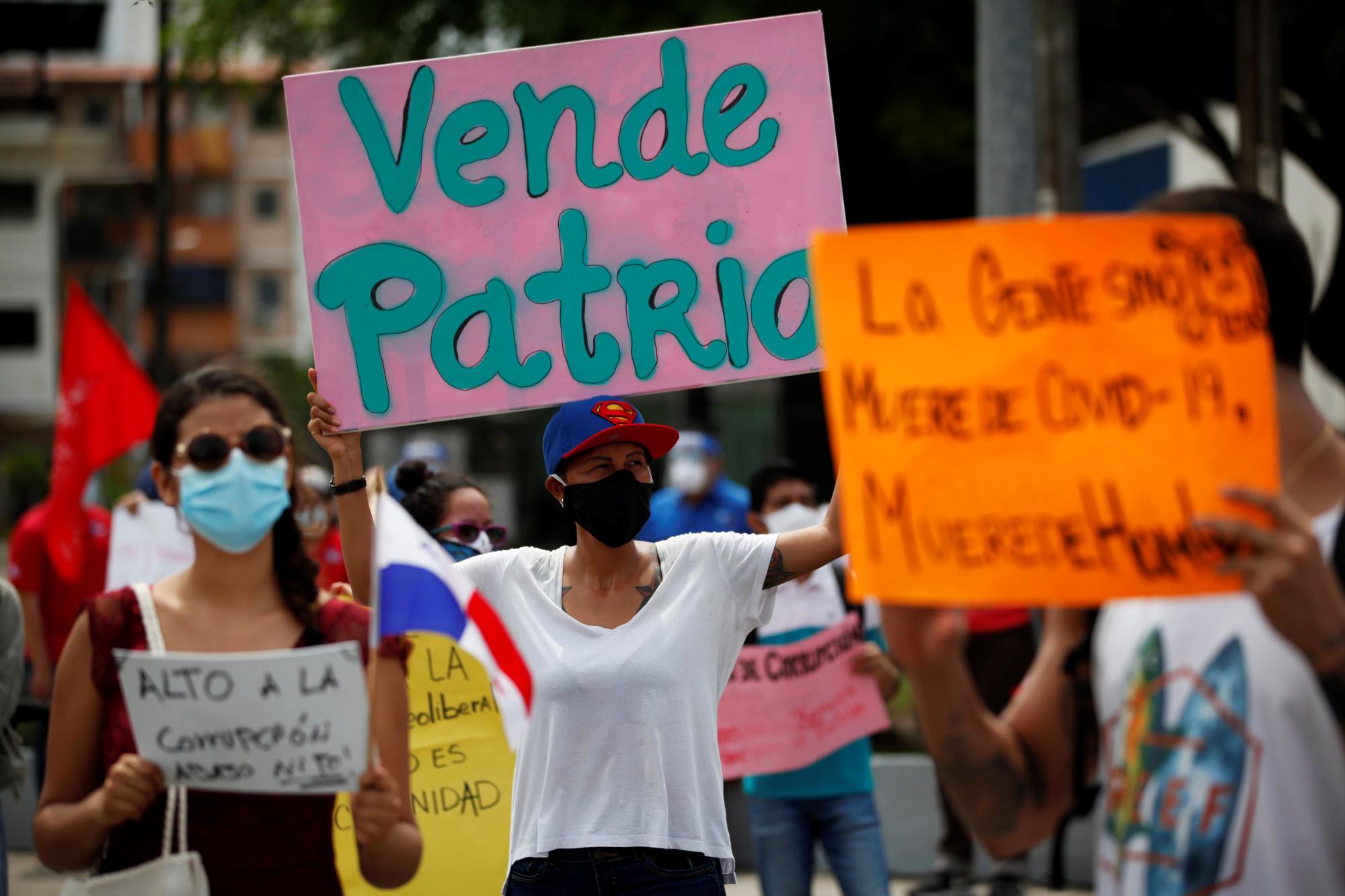 Varias personas sostienen carteles de protesta este miércoles, en las afueras de la Asamblea Nacional de Panamá, en donde el presidente de la nación, Laurentino Cortizo (EFE/ Bienvenido Velasco)