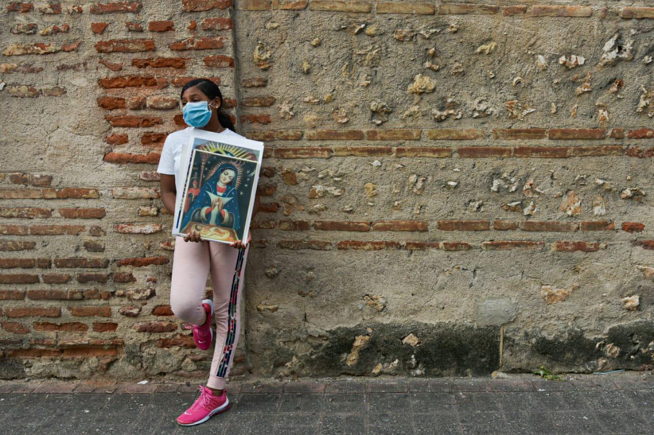 Una joven que vende imágenes de la Virgen de la Altagracia espera por los clientes en una calle de la Zona Colonial (Dania Acevedo)