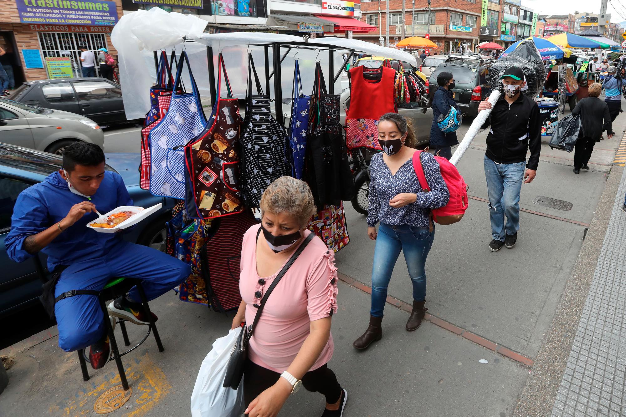 Clientes caminan por una zona comercial el 14 de agosto de 2020, en el barrio La Alquería de Bogotá (Colombia). 
