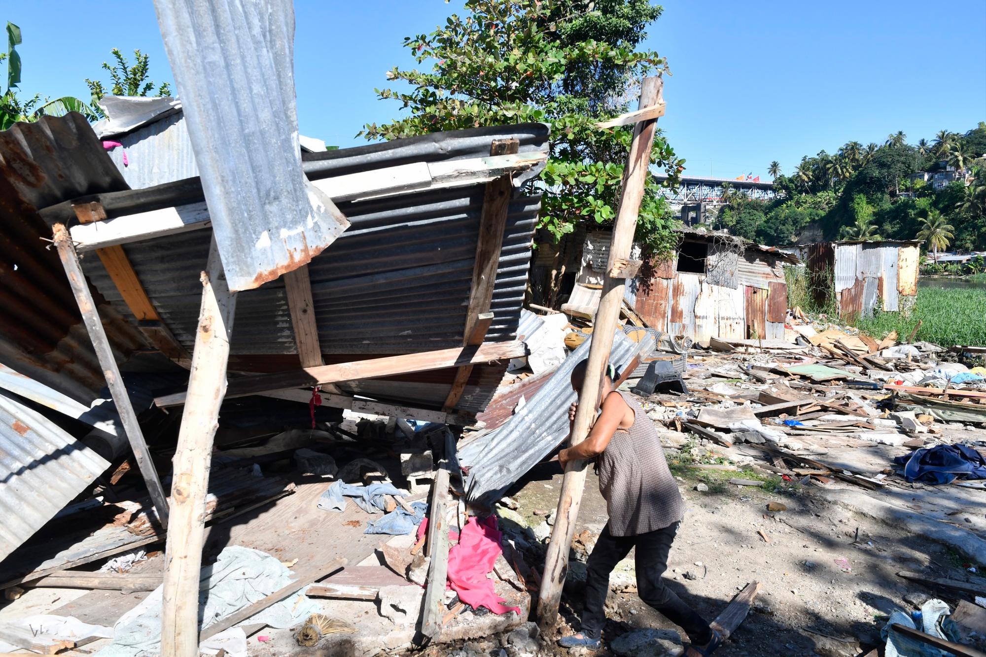 La señora Élida Altagracia, de 71 años, intenta concluir de derribar un palo de la vivienda en la que, dice, residía su hija Aurelia Guerrero con sus seis hijos. Calificó como “abuso” lo que el Gobierno hizo con su hija.