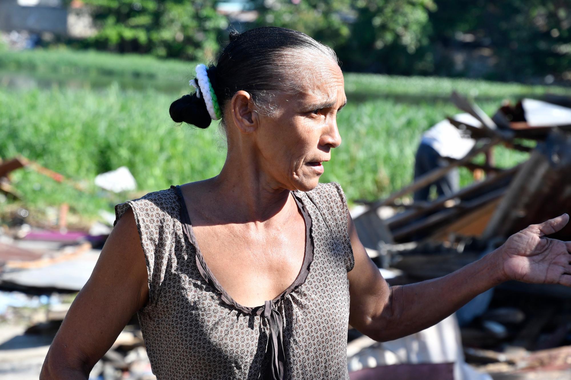 La señora Élida Altagracia ayuda a recoger los trastos de su hija Aurelia Guerrero luego de que la casucha en donde esta última vivía con sus seis hijos.