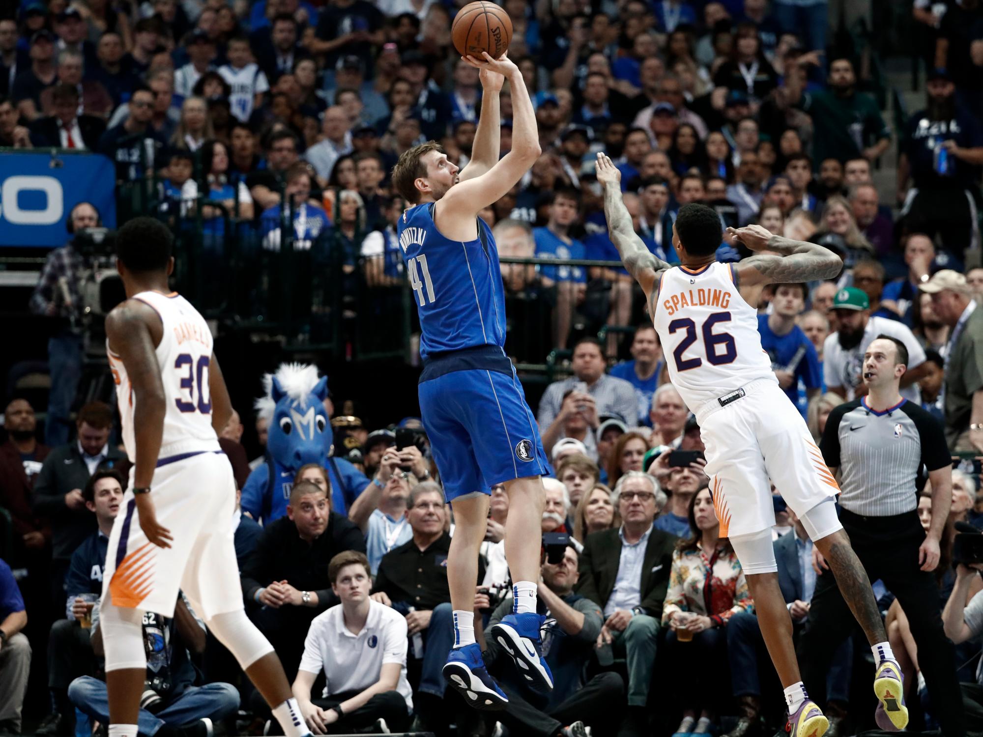 Troy Daniels (30) de los Phoenix Suns observa mientras el delantero Ray Spalding (26) intenta evitar un disparo de Dirk Nowitzki (41) de los Dallas Mavericks durante la primera mitad del partido en Dallas, el martes 9 de abril de 2019.