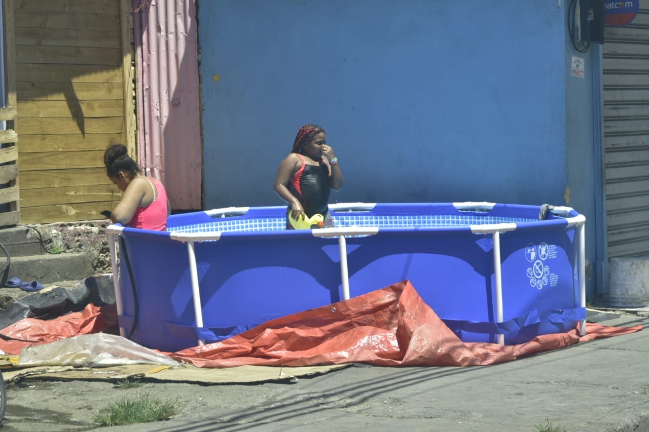 Dos niñas aprovechan el asueto de este Viernes Santo para bañarse en una piscina plástica en un sector del Distrito Nacional.