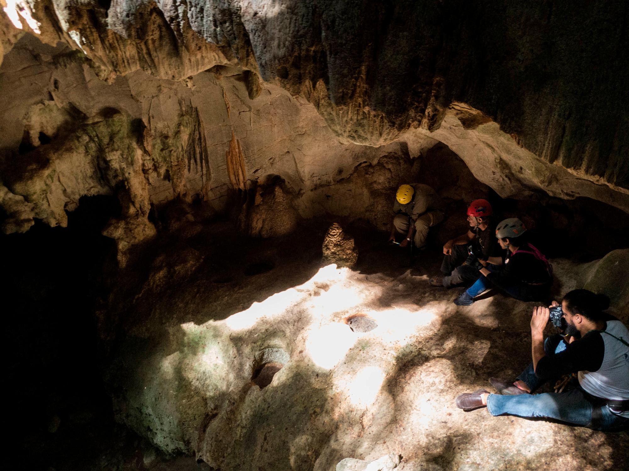 Marvin del Cid (primero de la izquierda) toma imágenes a la 1 de la tarde, cuando los rayos de sol tocan la base de la estalagmita, el 21 de diciembre de 2018.