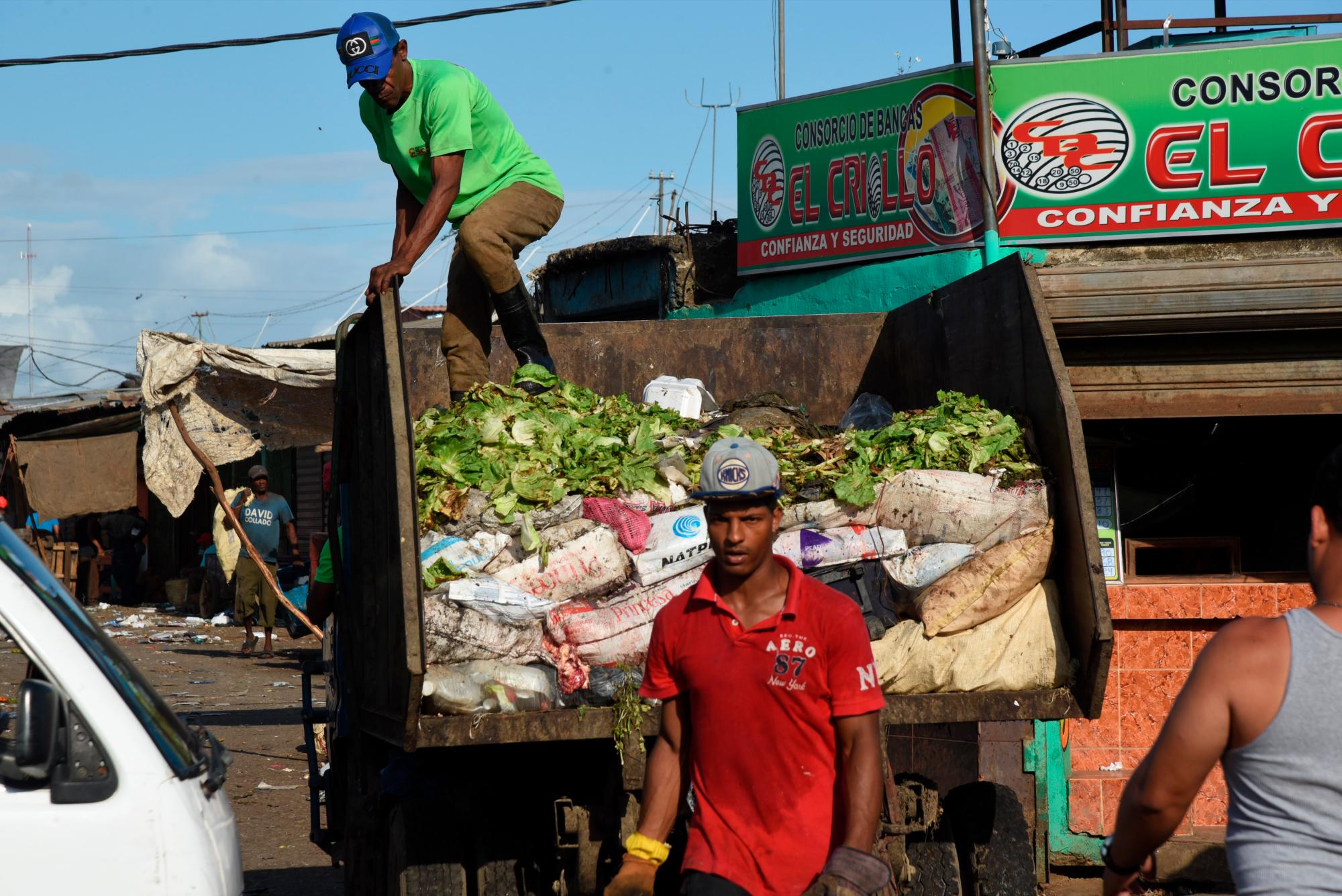 Camiones entran a recoger la basura al caer la tarde.