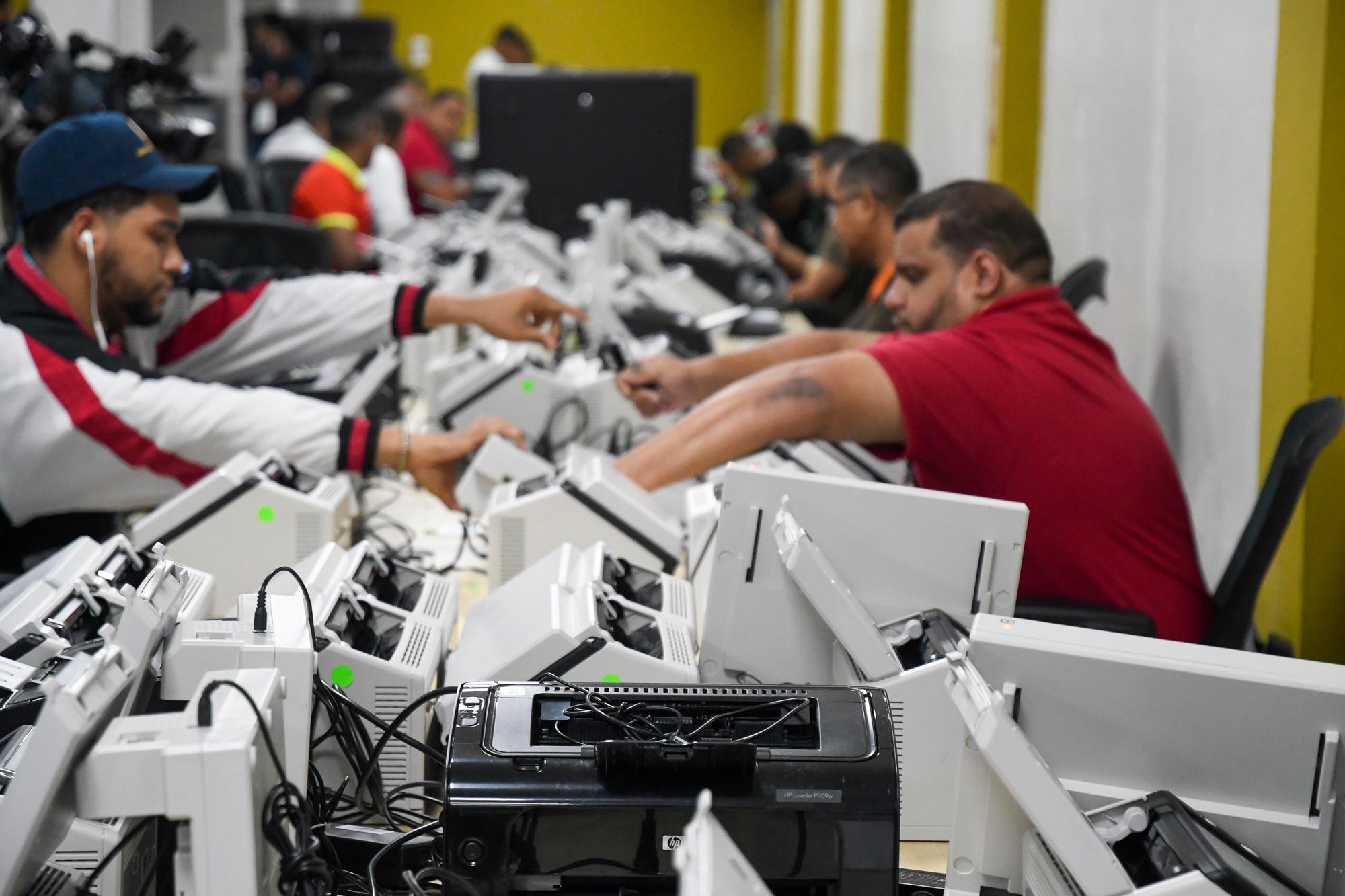 Téncicos de Informática de la JCE trabajan en el proceso de clonación de los escáneres.