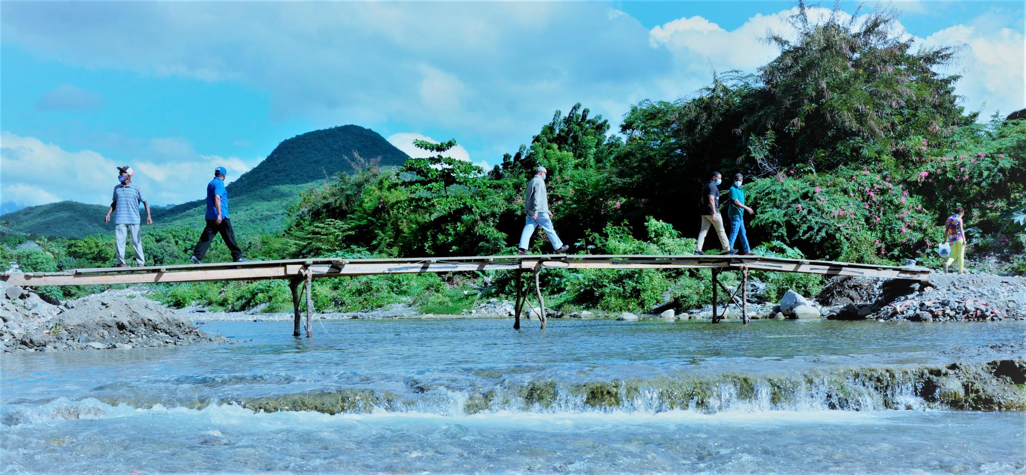 Personas caminando sobre un puente en malas condiciones.