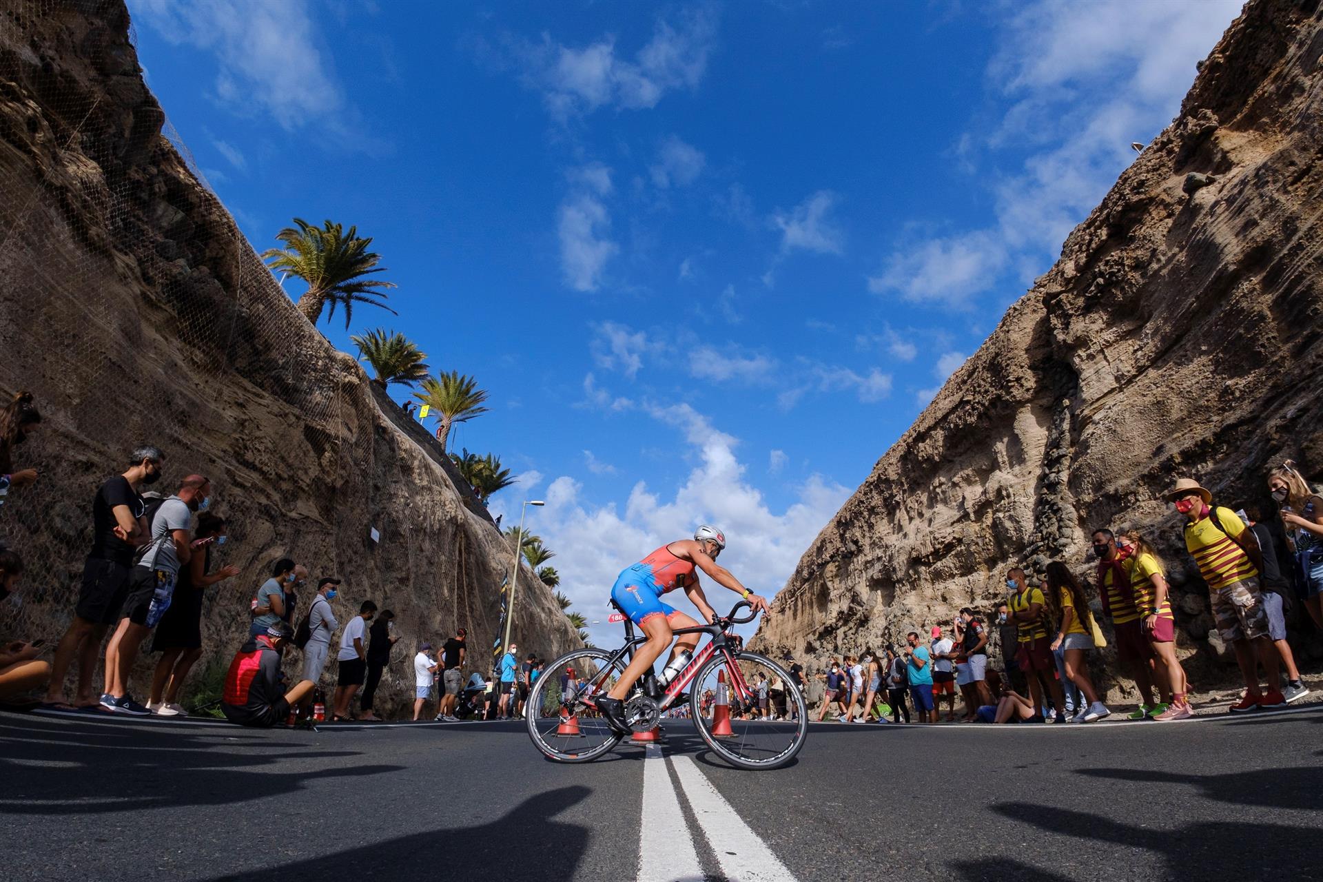 El sur de Gran Canaria acogió este sábado el primer triatlón Challenge que se celebra en Europa tras la pandemia de coronavirus, en la imagen uno de los atletas pasa junto a unos aficionados en la prueba de bicicleta. EFE/Ángel Medina G.