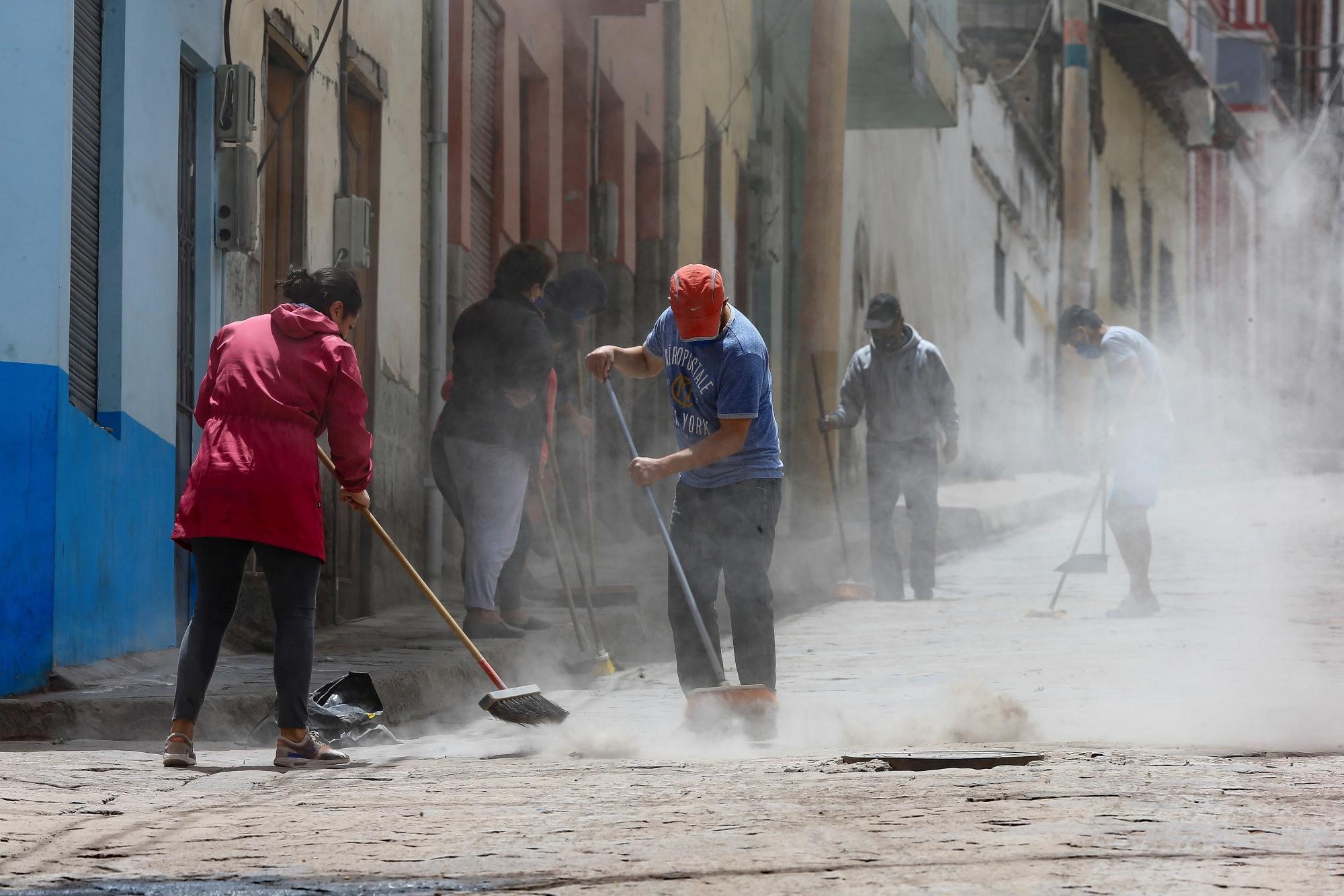 Habitantes barren hoy la ceniza del volcán Sangay en una calle de Alausí, en la provincia de Chimborazo (Ecuador). (EFE/José Jácome)