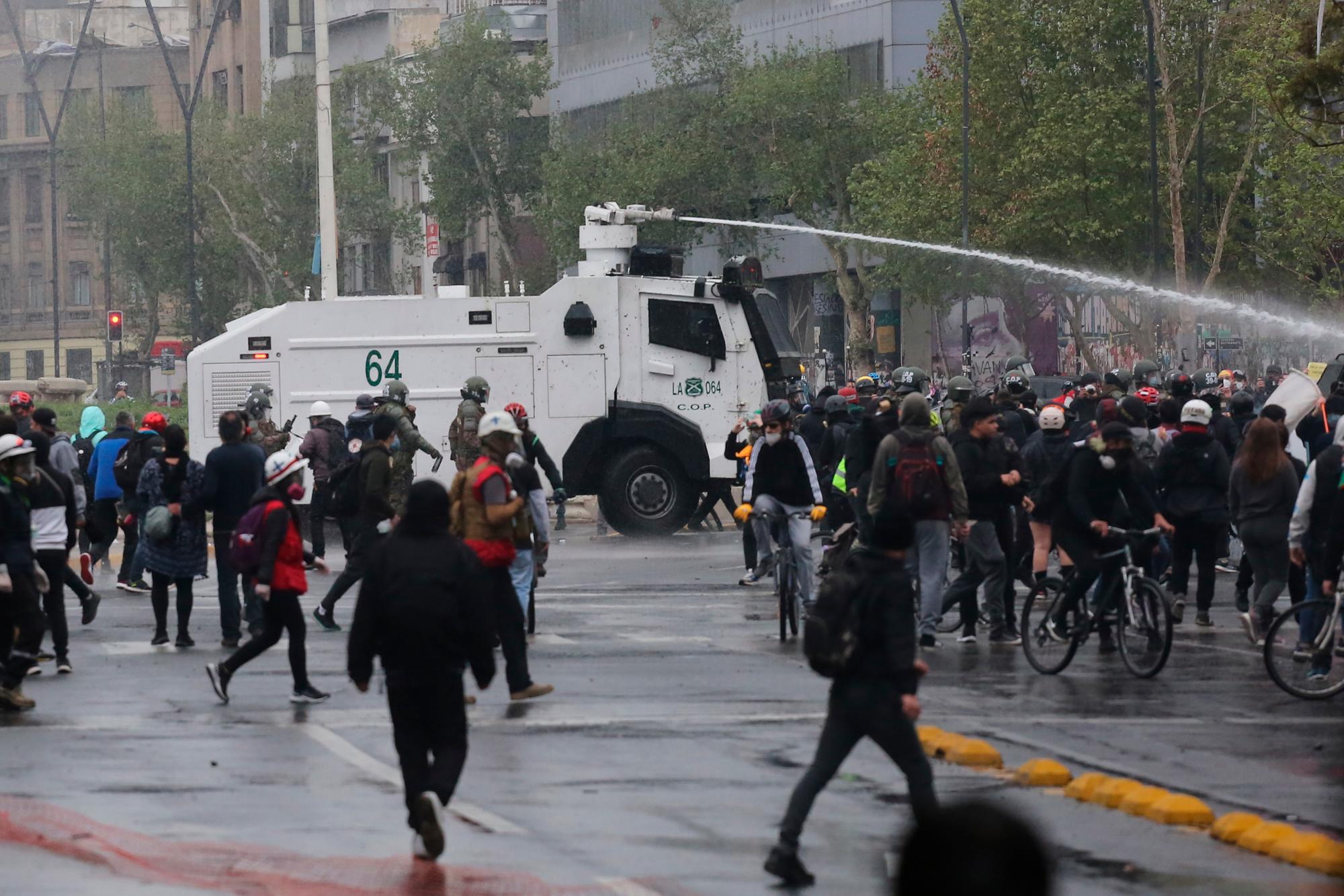 AME7450. SANTIAGO (CHILE), 25/09/2020.- Un vehículo antidisturbios de la policía intenta dispersar una protesta en contra del Gobierno del presidente chileno Sebastián Piñera hoy, en la plaza Italia en Santiago (Chile). 