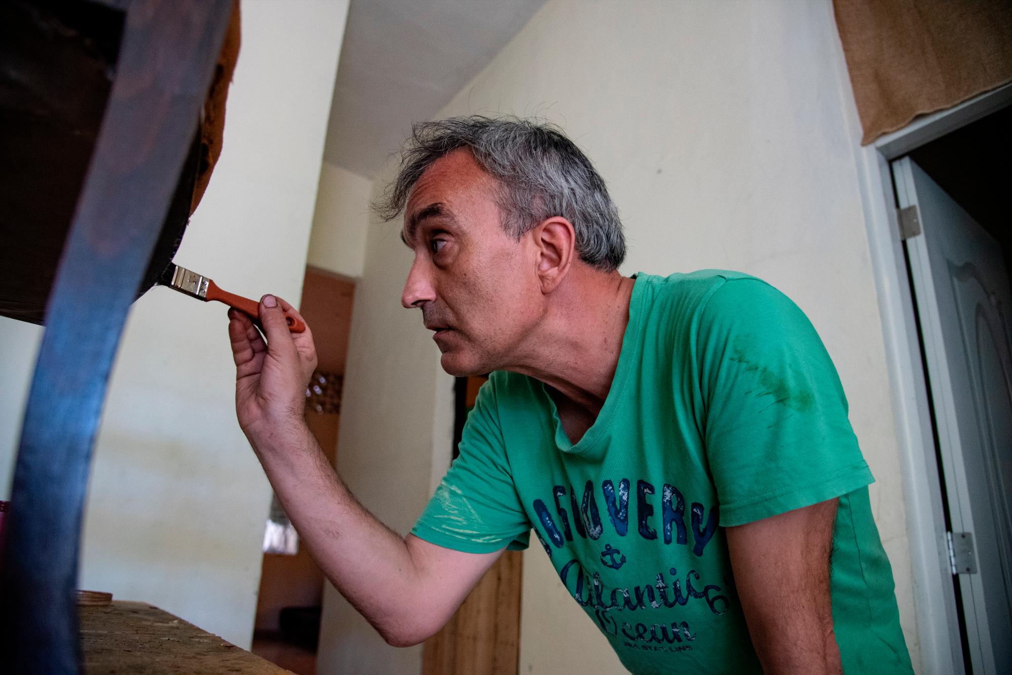 Jordi aplica barniz a una silla antigua en su taller.