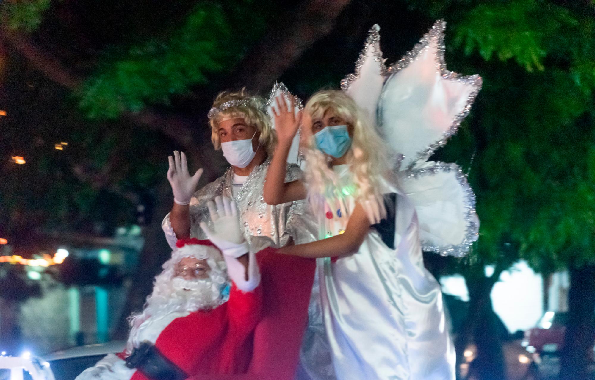 Santa Claus junto a otros personajes saludando a los ciudadanos.