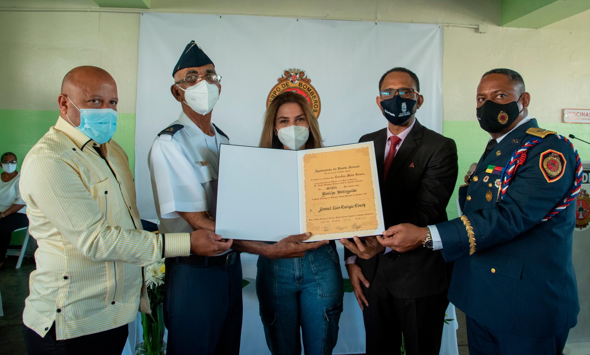 Luis Elsevif recibe la resolución de la mano de la alcaldesa y del presidente del Concejo de Regidores, Víctor Ogando, del jefe de los Bomberos y un regidor.