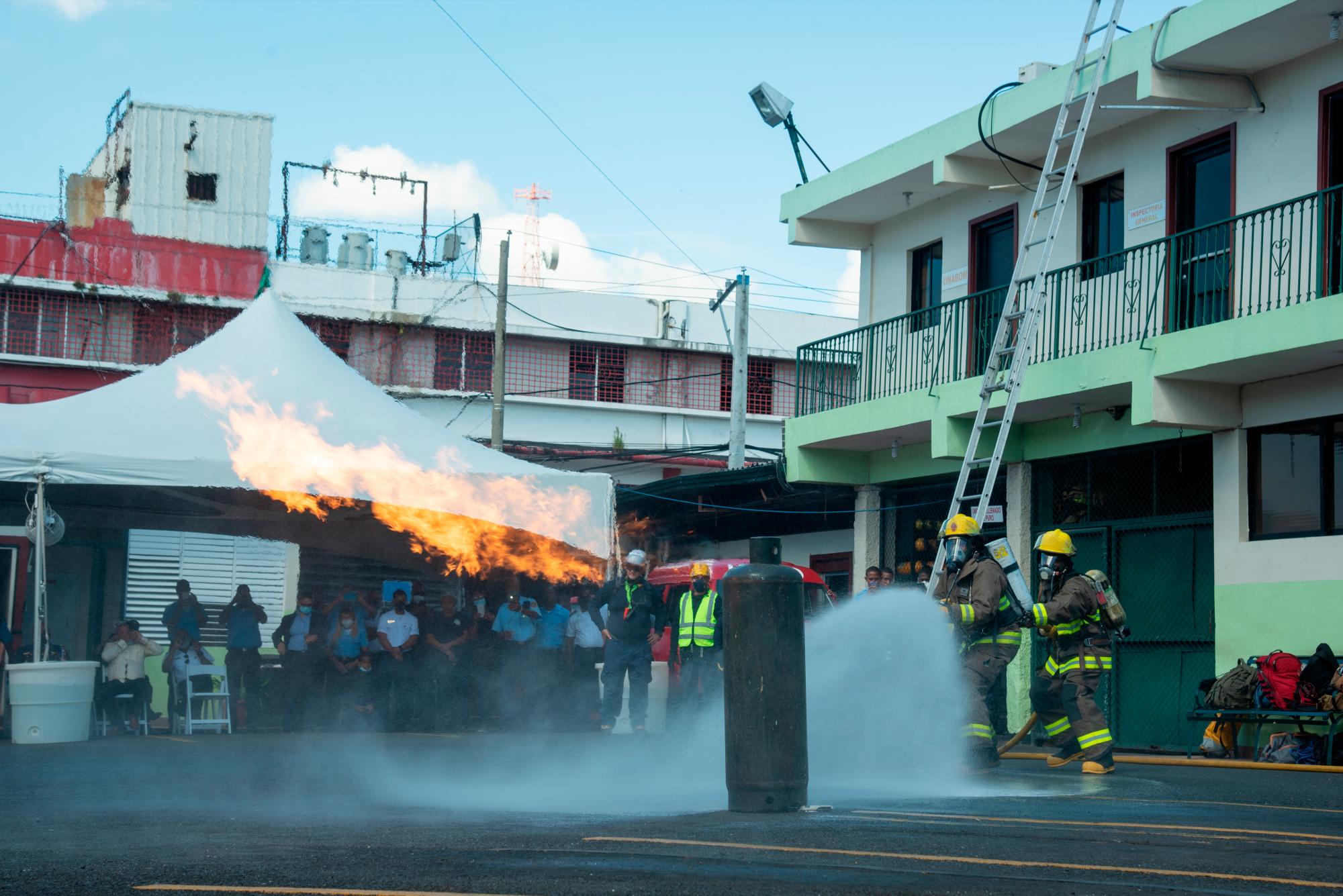 Bomberos hacen una exhibición de cómo enfrentar un cilindro de gas incendiado. 