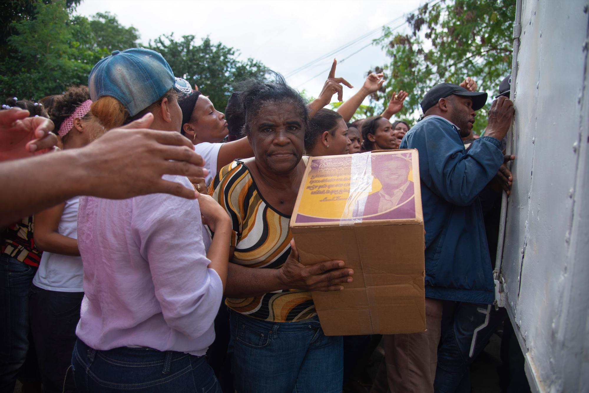 Una anciana carga con una caja con la foto del expresidente Leonel Fernández.