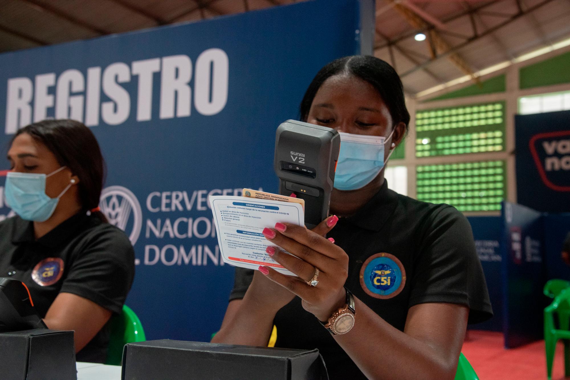 Voluntarios escanean datos para agregar al portal de vacunación.