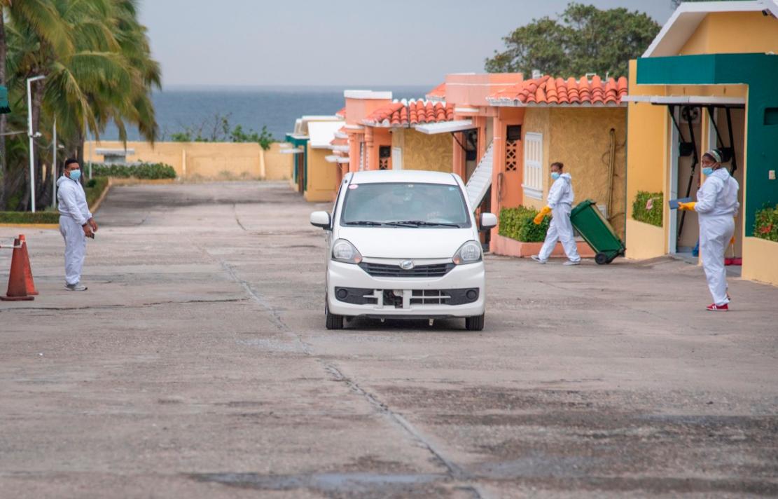 Empleados usan trajes de protección para limpiar las cabañas.