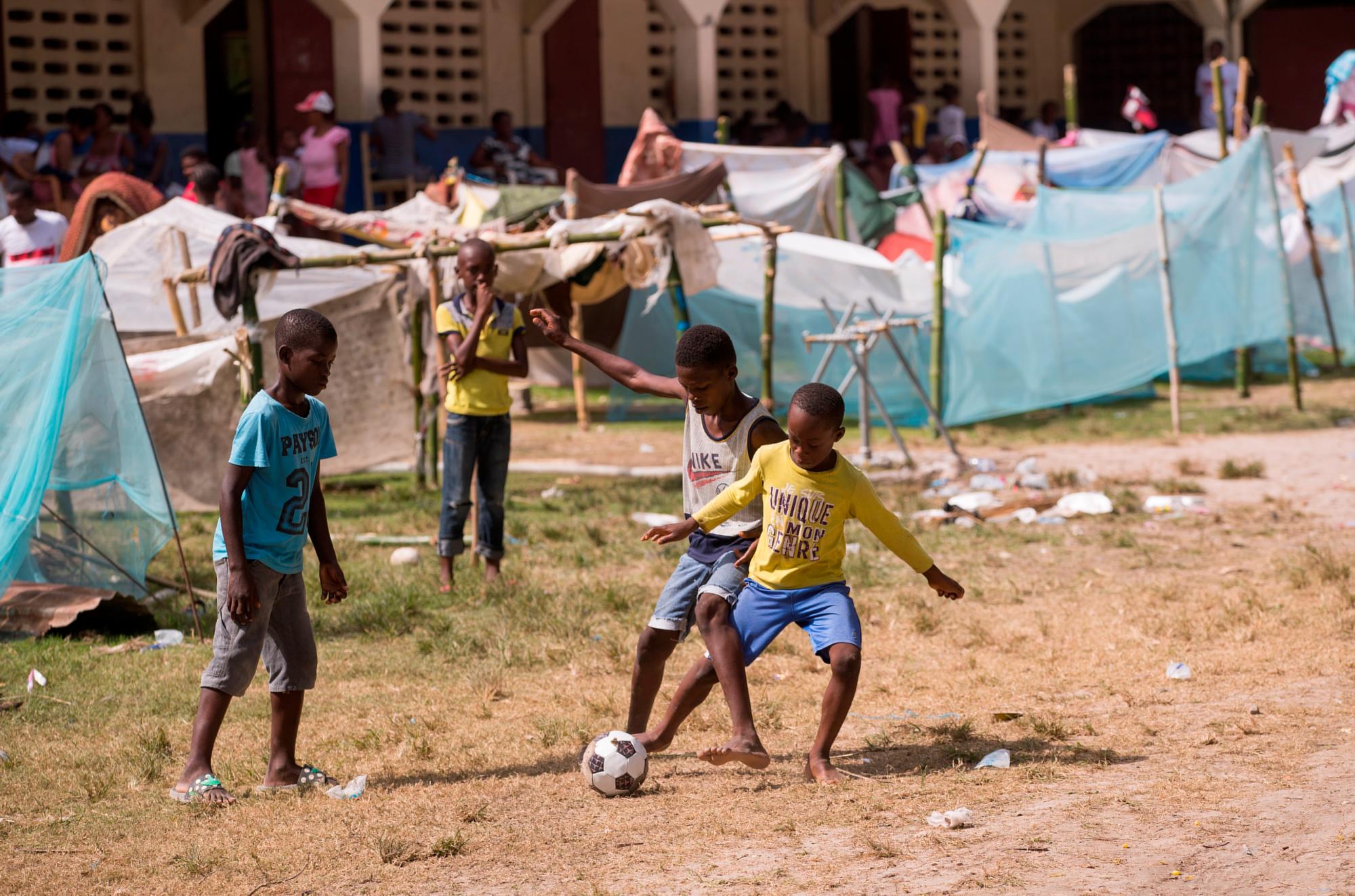 Niños juegan fútbol hoy, en un campamento para personas afectadas por el terremoto en las afueras de Les Cayes (Haití). El terremoto registrado el sábado pasado, de magnitud 7,2, afectó principalmente al sur de Haití, causó al menos 2.189 muertos y 12.268 heridos, y dejó 332 desaparecidos, según el último balance oficial, divulgado el pasado miércoles. EFE/Orlando Barría