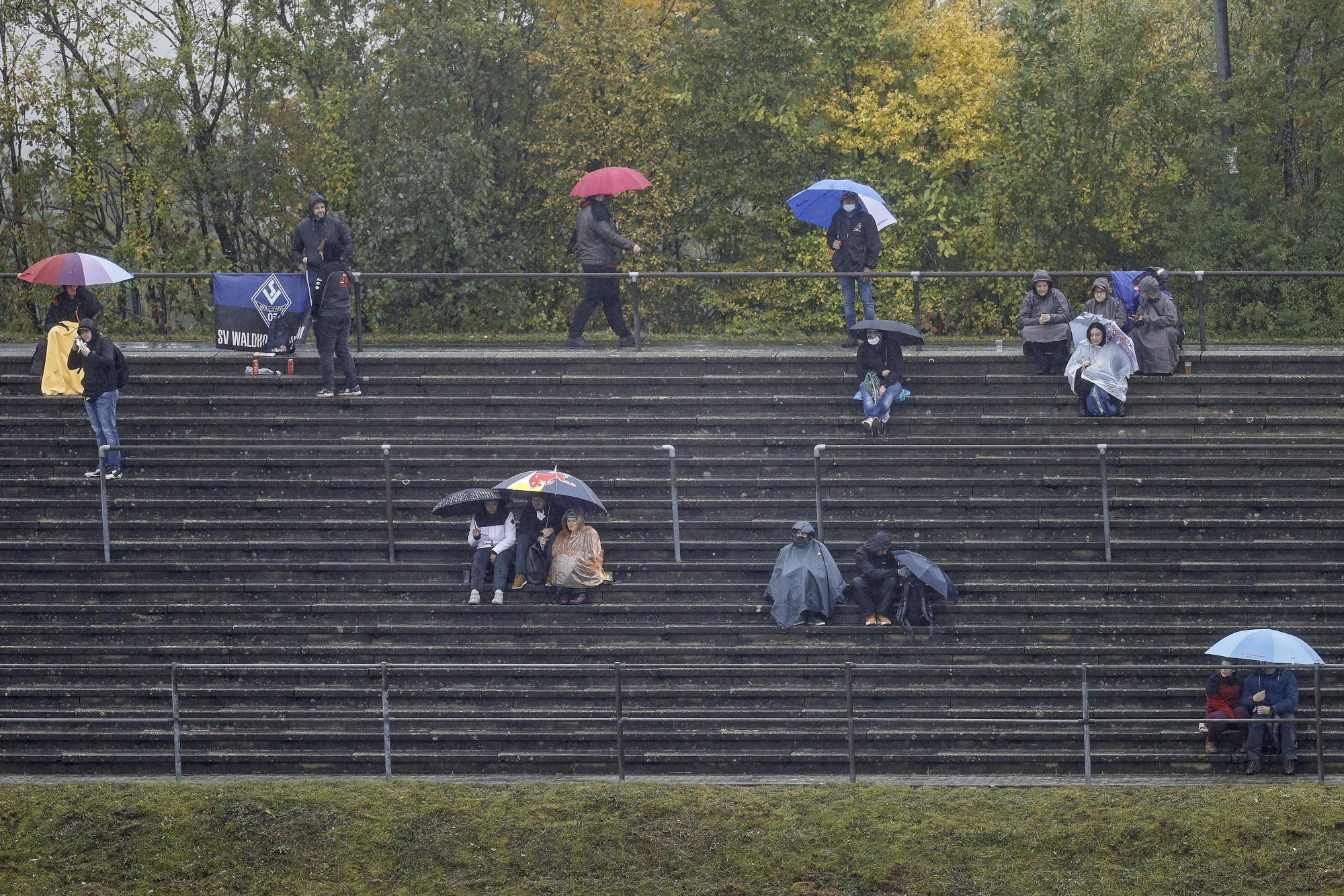 Los espectadores esperan en las gradas bajo la lluvia mientras el inicio de la primera sesión de entrenamientos se retrasa durante el Gran Premio de Eifel de Fórmula Uno. (EFE/Ronald Wittek)