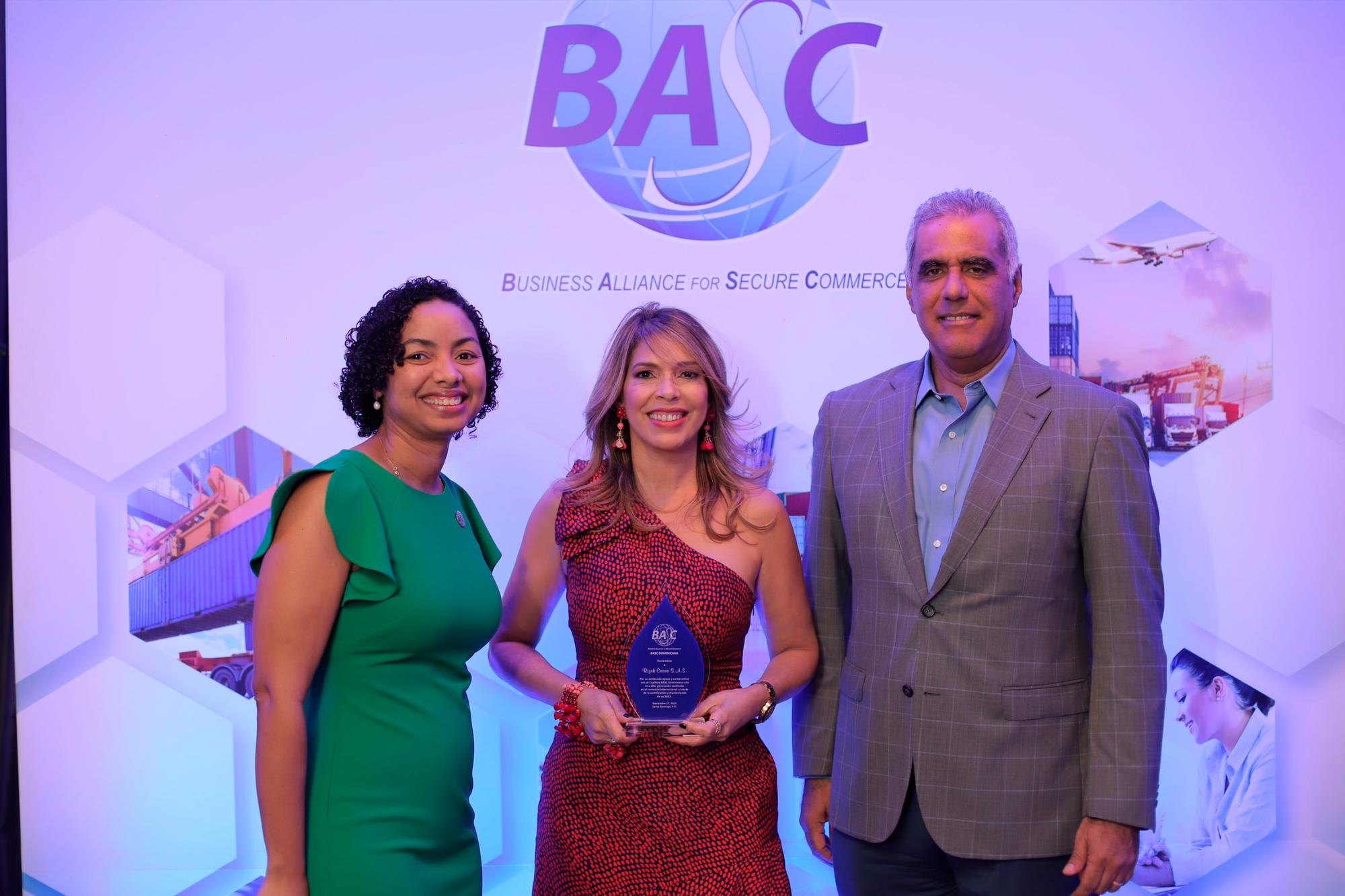 July de la Cruz y Armando Rivas entregan el reconocimiento a Mireya Abreu, de Rizek Cacao.