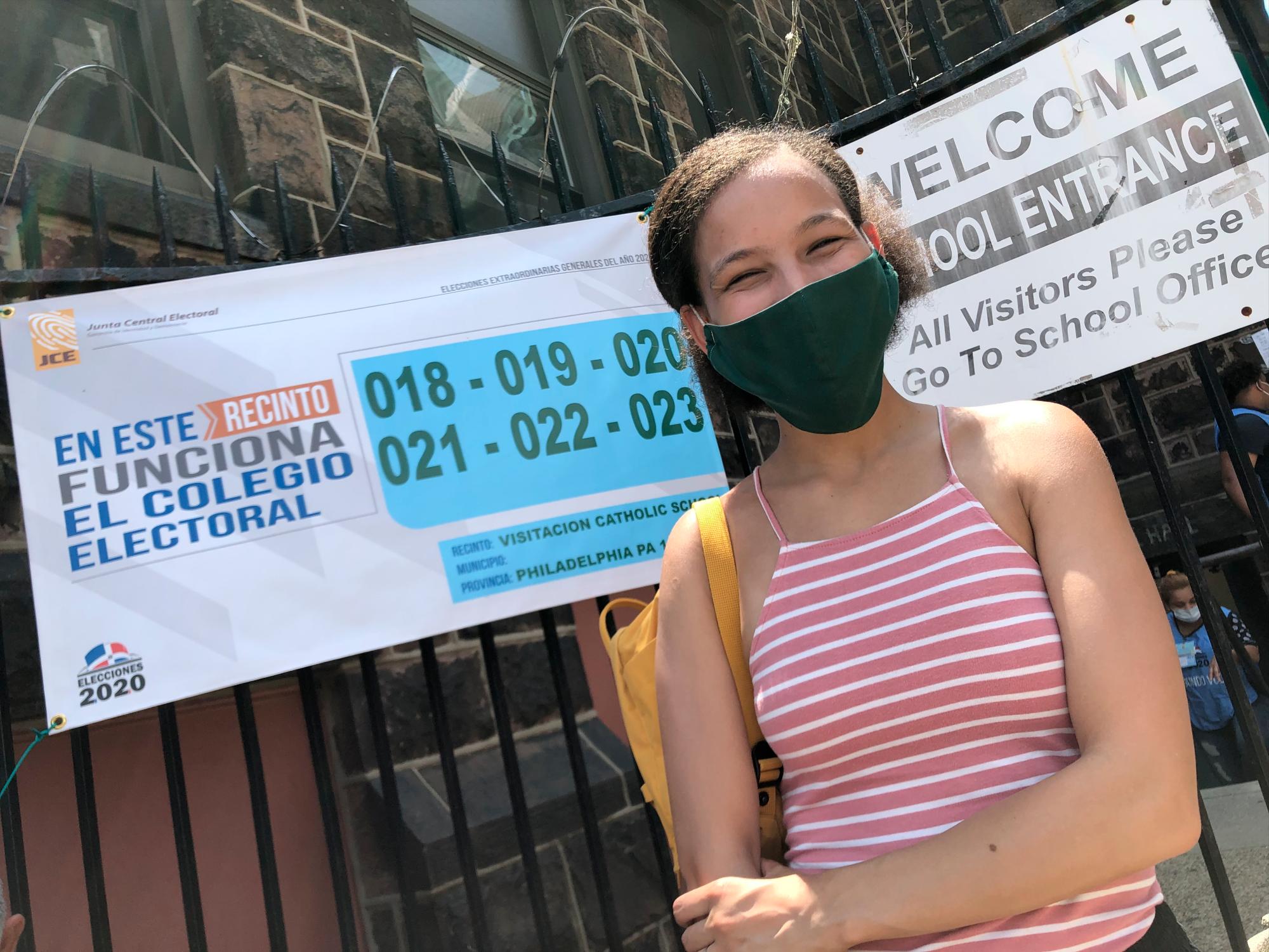 Mari González posa frente al recinto electoral, luego de ejercer su derecho al voto en el exterior por primera vez.