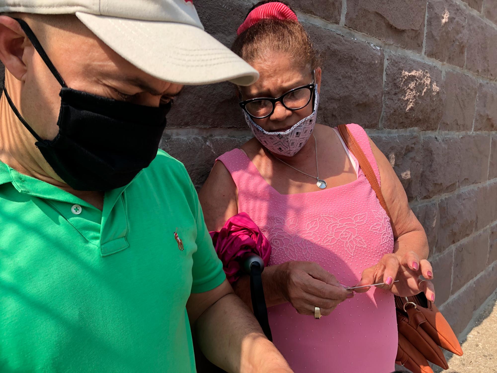 Miguel Bautista, de La Vega, ayuda a Eva Santana a verificar su recinto electoral.