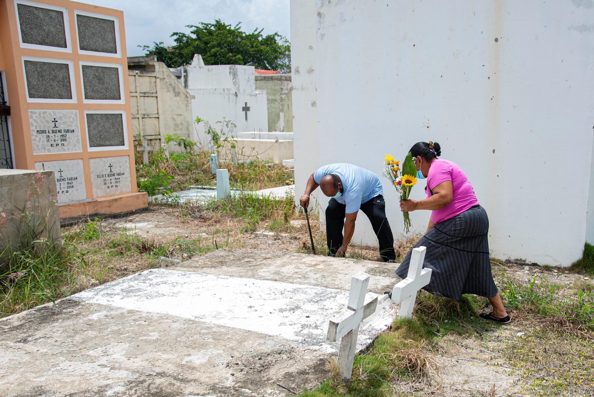 Un hombre y una mujer limpian y adornan con flores la tumba de su padre en el cementerio Cristo Redentor  de Santo Domingo, el domingo 26 de julio de 2020, día de los padres en República Dominicana. Foto: Dania Acevedo/Diario Libre