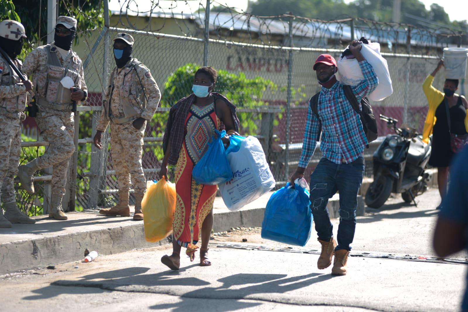 Personas cargan con mercancías este viernes en la frontera domínico-haitiana.
