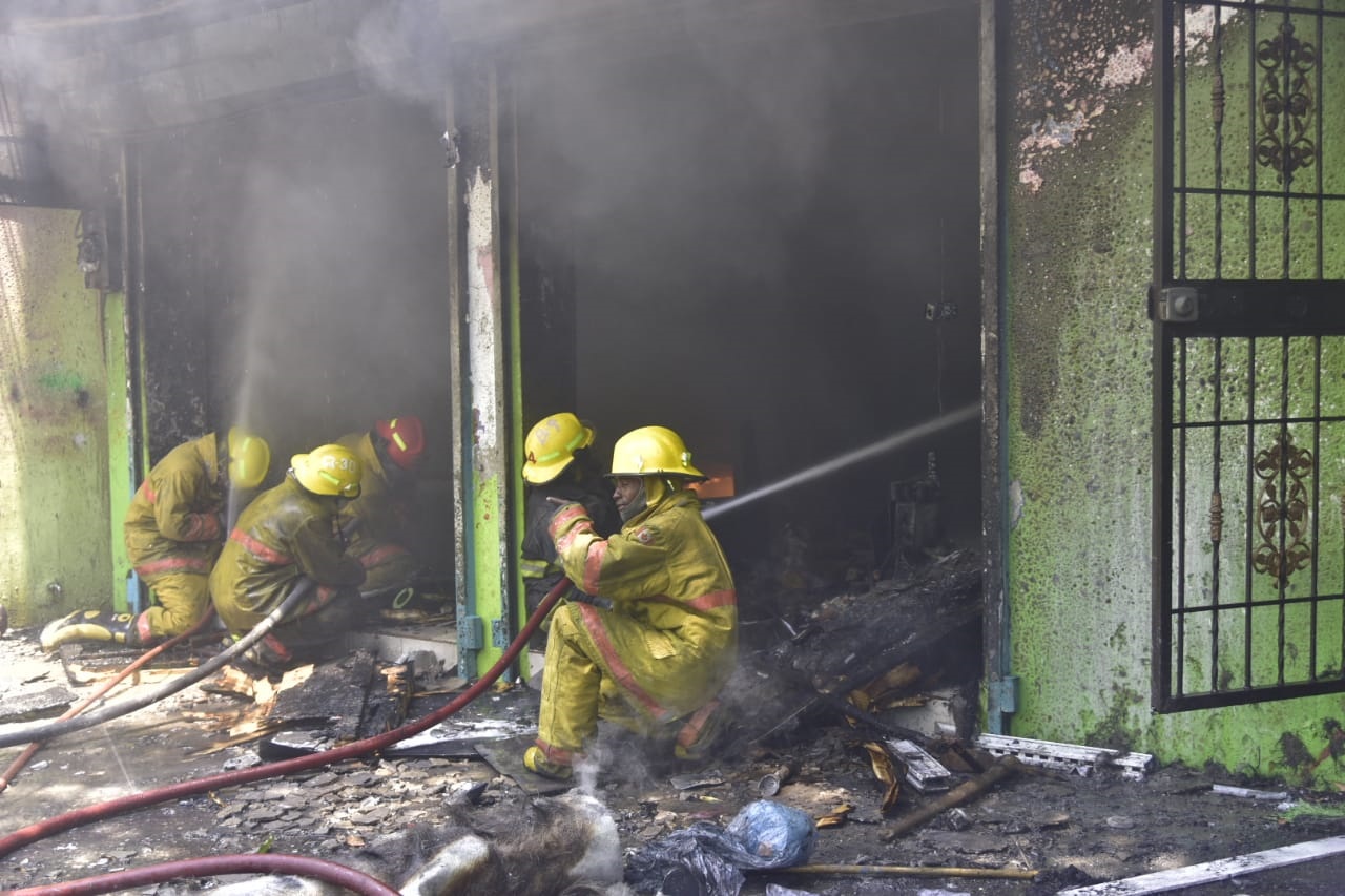 Los bomberos trabajan por sofocar el incendio en la tienda de pinturas automotriz y materiales afines en el ensanche La Paz.