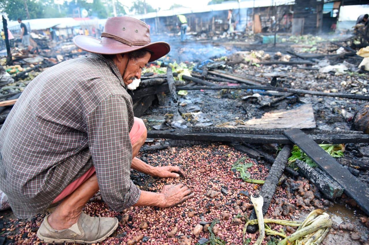 Un vendedor trata de salvar parte de los productos que ofertaba en el quemado mercado provisional de La Vega este jueves.