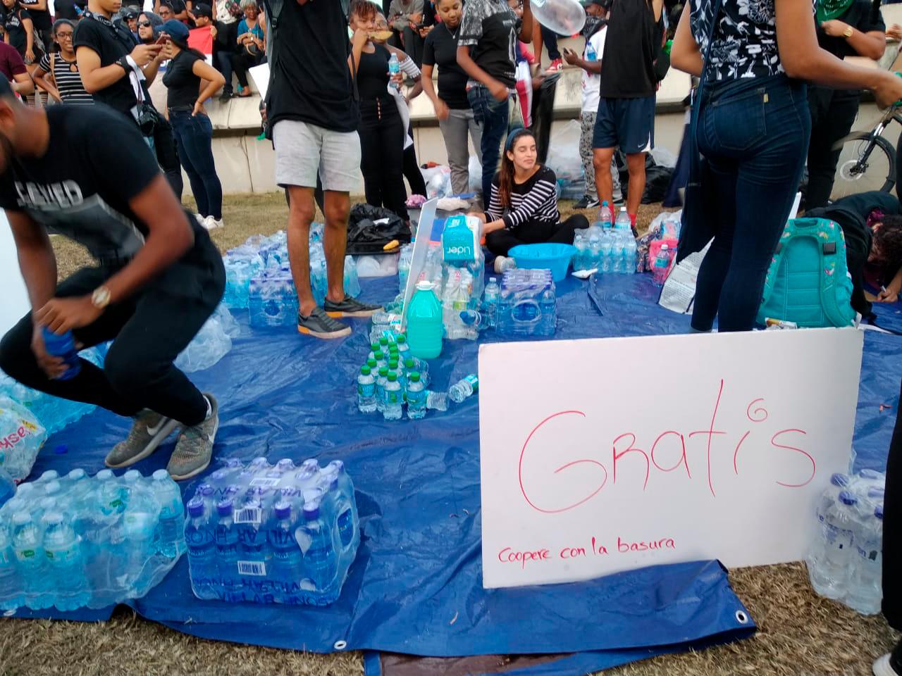 Jóvenes distribuyen agua entre los asistentes a la manifestación. 