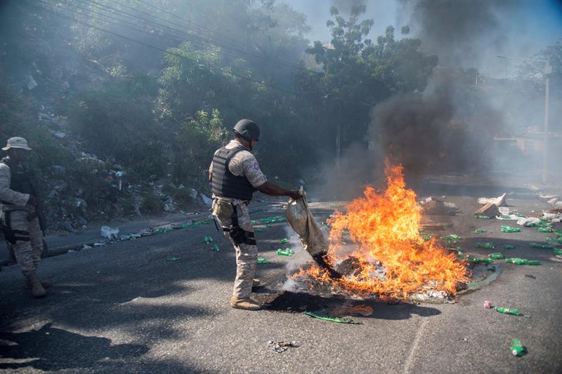 Un agente de la Policía Haitiana trata de apagar un neumático incinerado