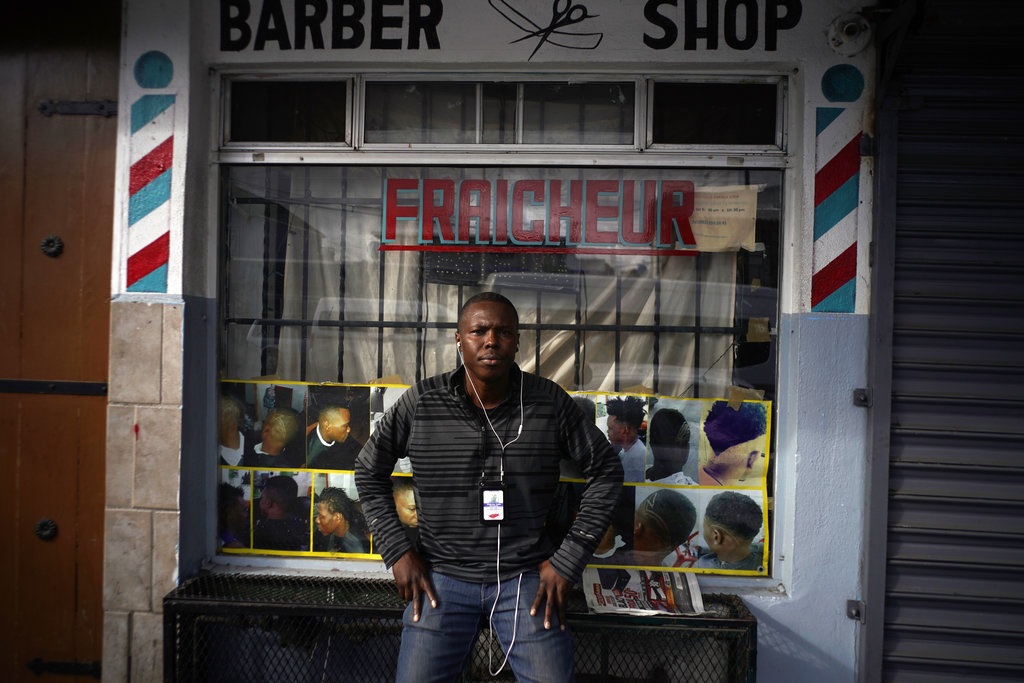 Philocles Julda, de 44 años, posa para una foto frente a una barbería haitiana en Tijuana, México, jueves 22 de noviembre de 2018.