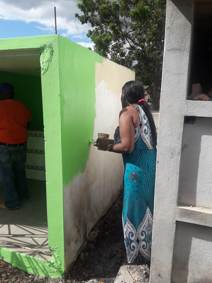 Dos integrantes de la familia pintando el nicho.