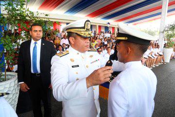 El comandante general de la Armada impone las insignias a uno de los graduandos.