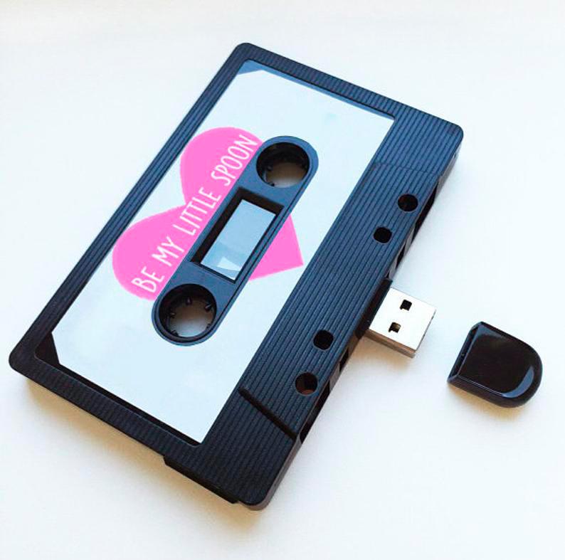 Puedes encontrar este original USB retro, que simula un cassette, en Etsy y personalizarlo.