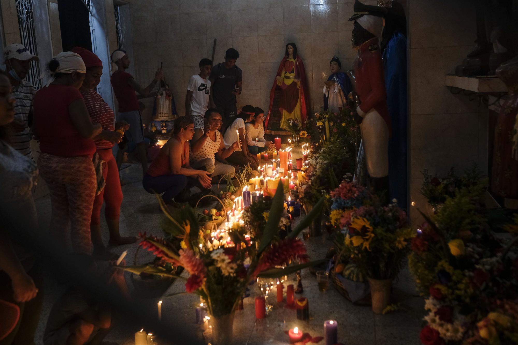 Los seguidores del culto de María Lionza colocan velas para una ofrenda en un altar en la montaña Sorte. (Foto AP / Matias Delacroix)