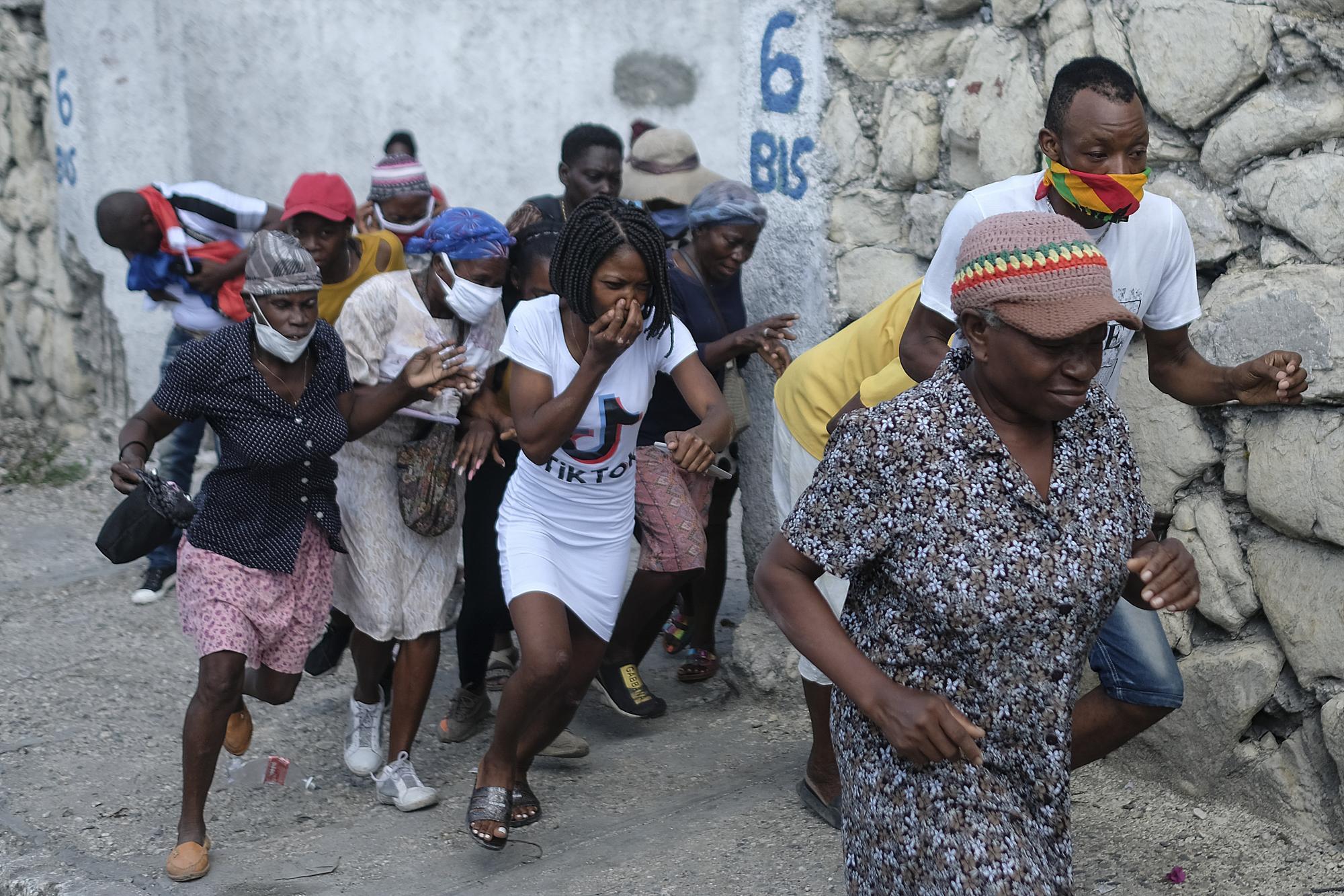 Las personas que marchaban hacia la residencia de los primeros ministros, para exigir justicia por el asesinato del presidente haitiano Jovenel Moise, huyen de los gases lacrimógenos disparados por la policía en Puerto Príncipe, Haití, el miércoles 20 de octubre de 2021. (AP Photo/Matias Delacroix)
