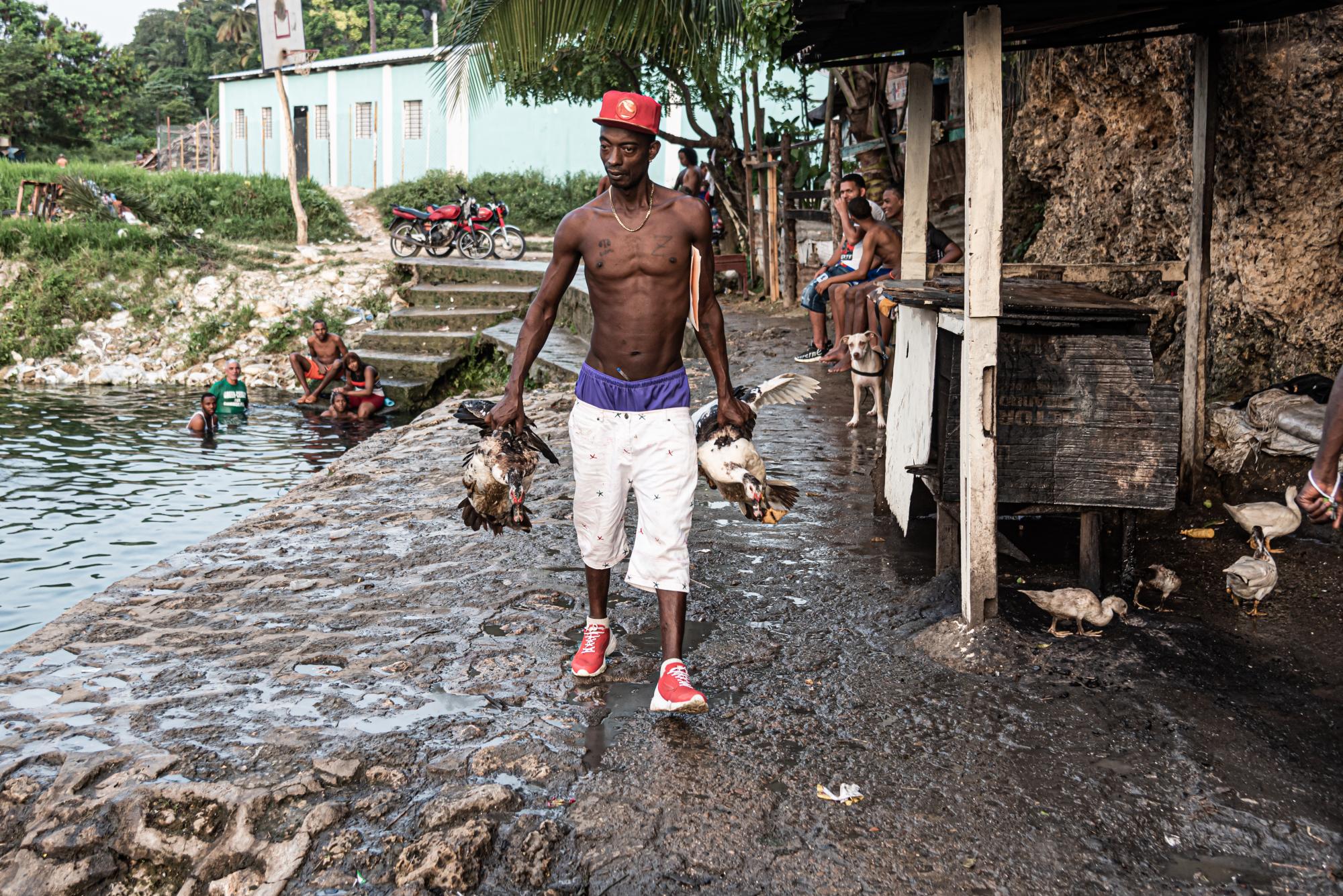 Un hombre camina en los alrededores de la poza vendiendo patos, mientras otras personas se bañan. (Foto: Eddy Vittini)