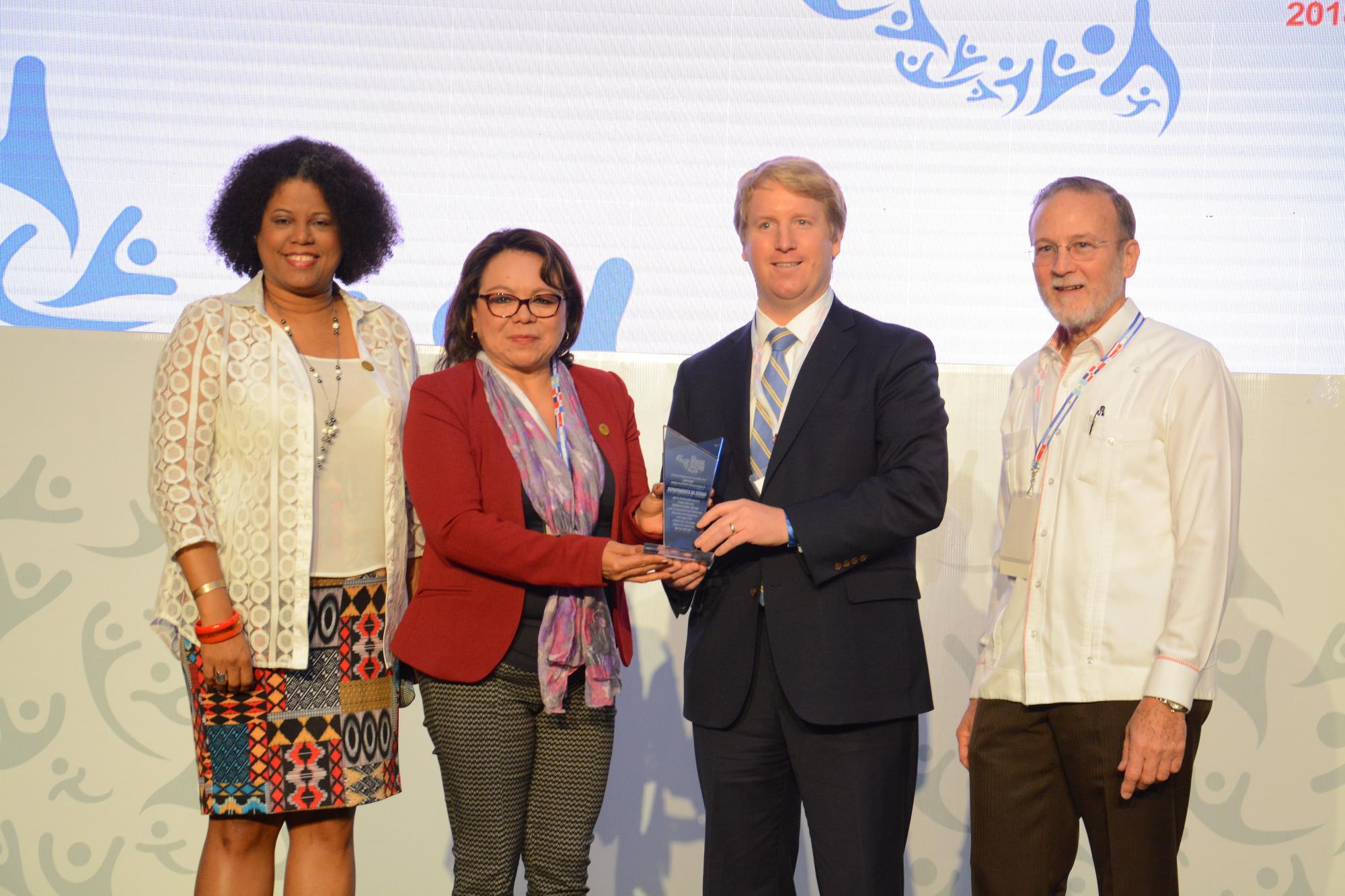 Brett Klansik, representante del Departamento de Estado de los Estados Unidos, recibe el reconocimiento que le otorgó Centromype.