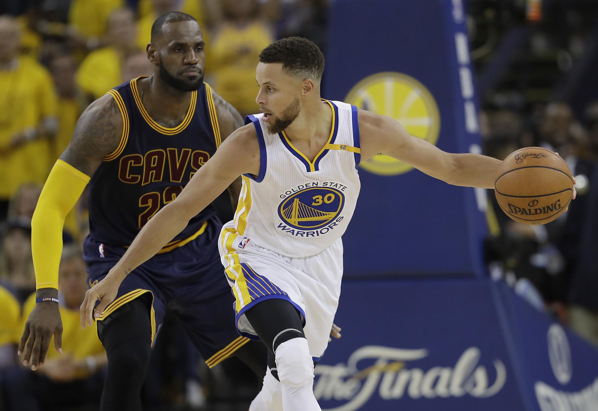 El guardia de Golden State Warriors Stephen Curry (30) es custodiado por el alero Cavaliers de Cleveland LeBron James en la final del 2016-17.