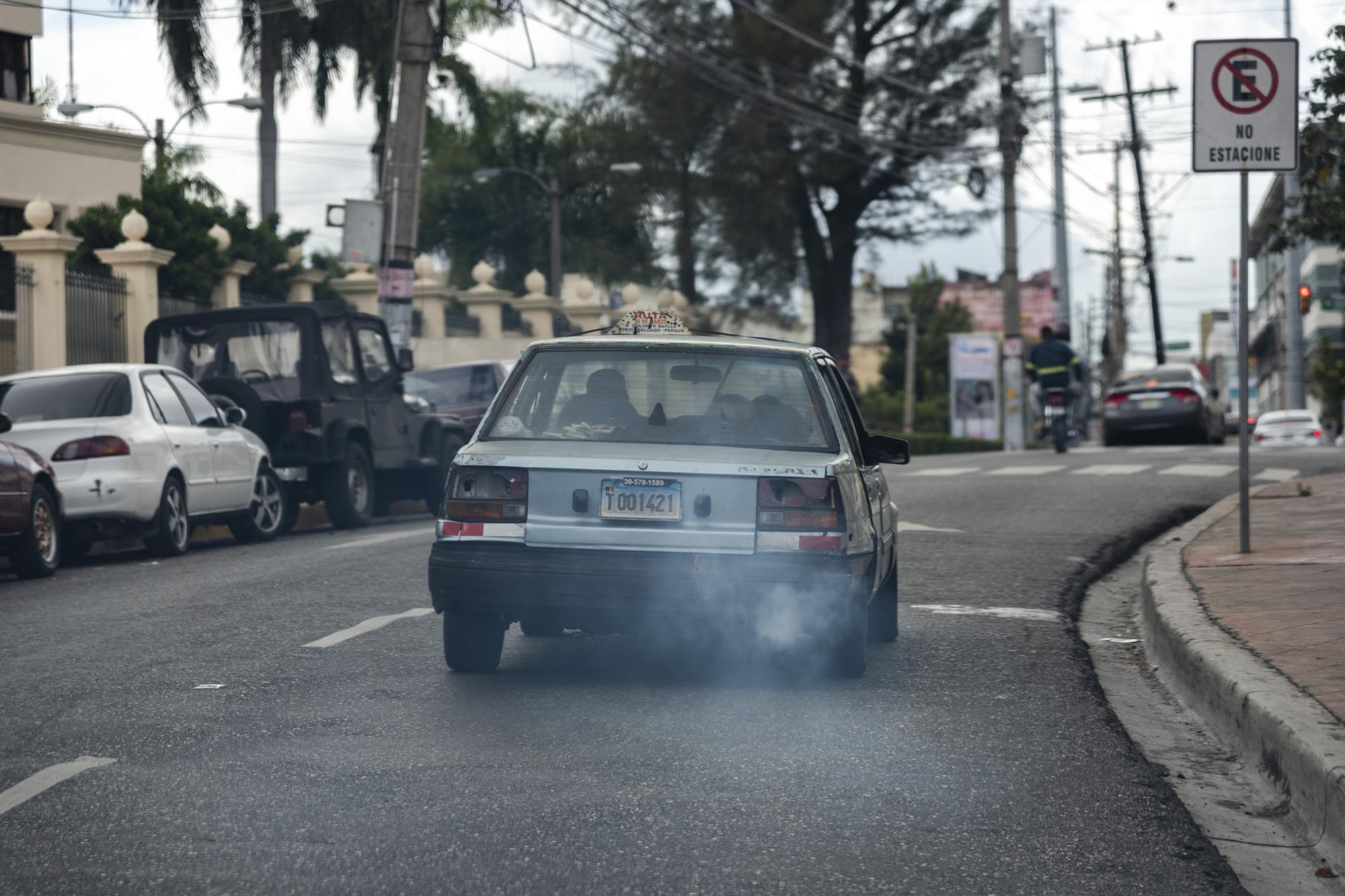 Un carro de concho, con más años de los que desearía su dueño, deja un rastro de humo mientras se desplaza por una calle de la ciudad.