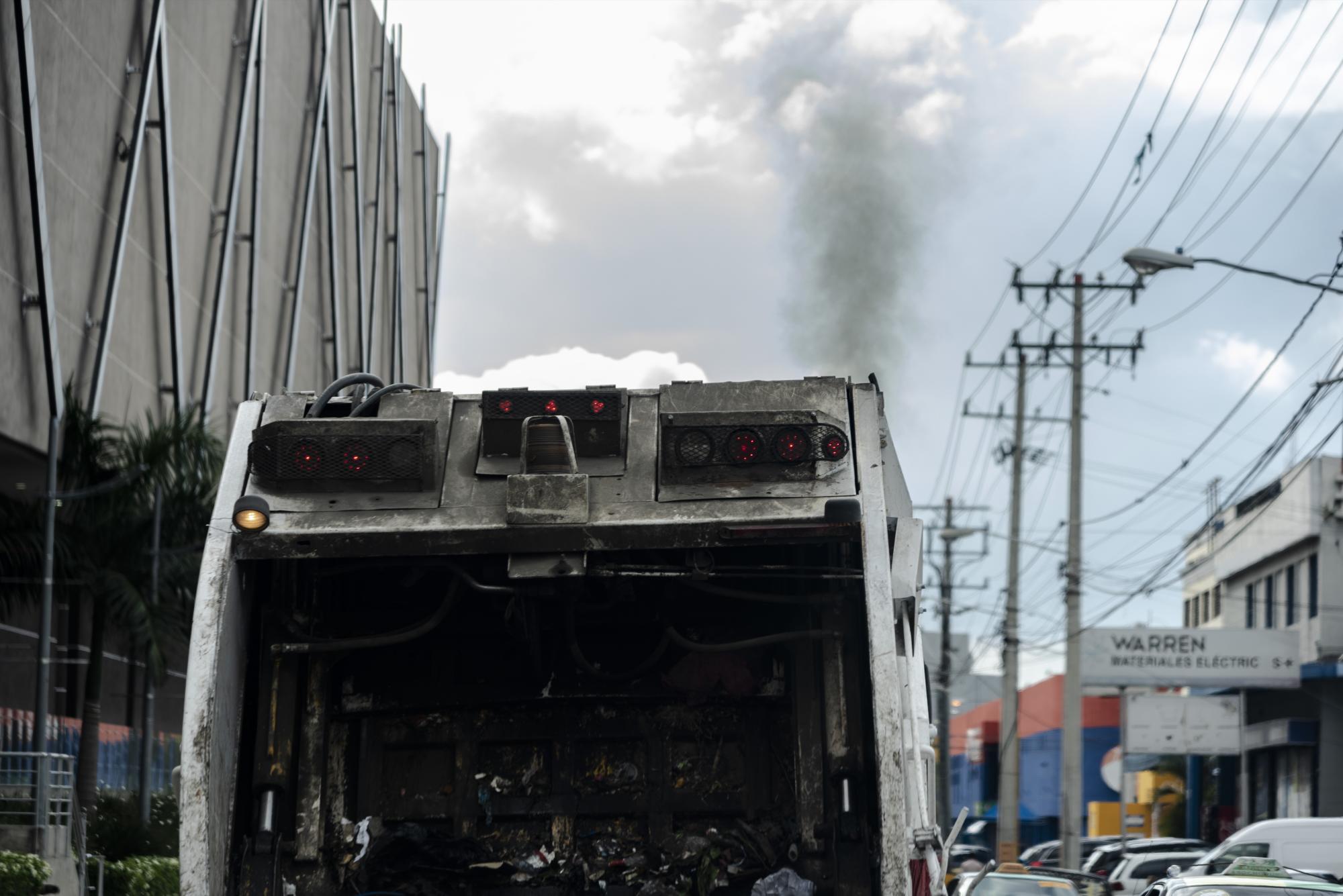 Un camión del servicio de recolección de residuos se traslada humeante por la avenida San Martín, en la Distrito Nacional.