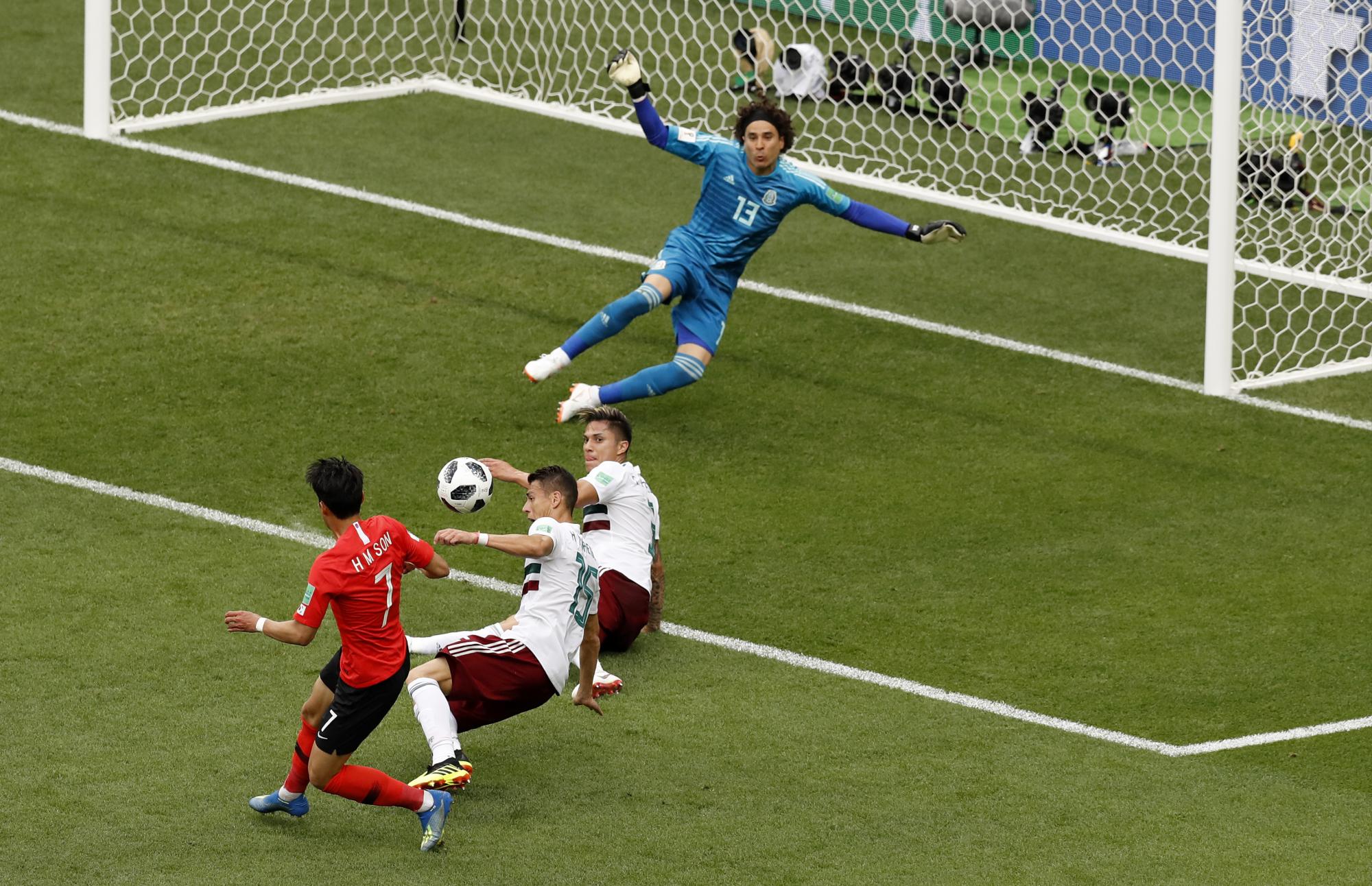 El surcoreano Son Heung-min, izquierda, apunta al arco mientras los mexicanos Héctor Moreno y Miguel Layun bloquean su disparo cuando el portero mexicano Guillermo Ochoa reacciona durante el partido del grupo F entre México y Corea del Sur en la Copa Mundial de fútbol 2018.